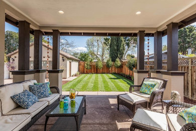 Example of a mid-sized transitional backyard stamped concrete patio design in San Francisco with a roof extension
