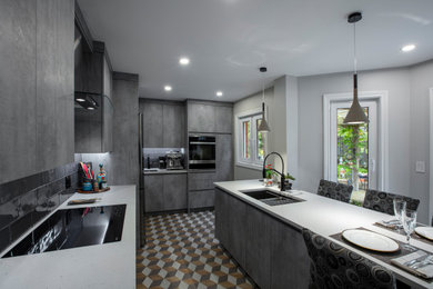 Mid-sized trendy l-shaped vinyl floor and multicolored floor enclosed kitchen photo in Toronto with an undermount sink, flat-panel cabinets, gray cabinets, quartz countertops, black backsplash, porcelain backsplash, black appliances, a peninsula and white countertops