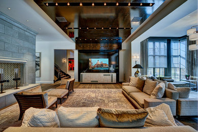 Photo of an expansive contemporary open concept family room in Miami with grey walls, medium hardwood floors, a two-sided fireplace, a stone fireplace surround, a wall-mounted tv and brown floor.