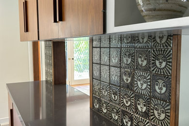 Home bar - large mid-century modern home bar idea in Los Angeles with medium tone wood cabinets, quartz countertops, multicolored backsplash and black countertops