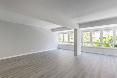 Modelo de salón abierto minimalista sin televisor con paredes grises, suelo laminado y suelo gris