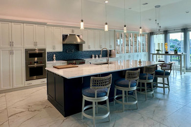 Huge beach style single-wall porcelain tile, multicolored floor and vaulted ceiling open concept kitchen photo in Houston with a single-bowl sink, shaker cabinets, white cabinets, quartz countertops, blue backsplash, glass tile backsplash, stainless steel appliances, an island and multicolored countertops