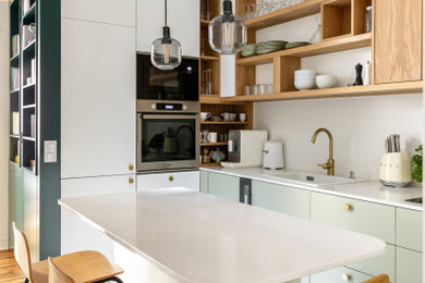 Réalisation d'une petite cuisine américaine encastrable et blanche et bois nordique en U avec un évier 1 bac, un placard à porte affleurante, des portes de placards vertess, un plan de travail en quartz, une crédence blanche, une crédence en céramique, parquet clair, îlot, un sol beige et un plan de travail blanc.