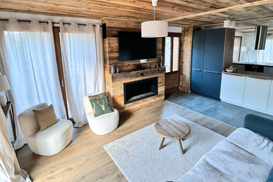 Cette image montre un grand salon chalet ouvert avec parquet clair, une cheminée ribbon, un manteau de cheminée en bois, un téléviseur fixé au mur et un plafond en bois.