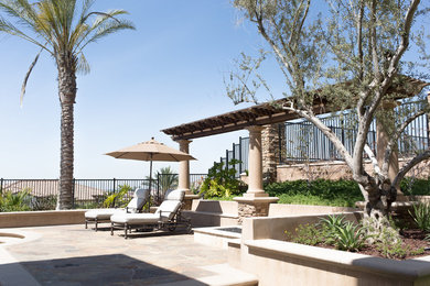 Large traditional backyard partial sun xeriscape in Orange County with natural stone pavers.