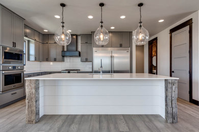 Farmhouse medium tone wood floor and gray floor kitchen photo in Other with an undermount sink, shaker cabinets, gray cabinets, quartzite countertops, white backsplash, subway tile backsplash, stainless steel appliances, an island and white countertops