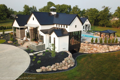 Example of a huge farmhouse white two-story metal and board and batten house exterior design in Other with a metal roof and a black roof