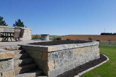 Photo of a large traditional full sun backyard brick retaining wall landscape in Other.