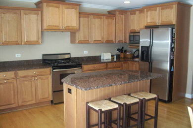Eat-in kitchen - huge u-shaped light wood floor eat-in kitchen idea in Chicago with an undermount sink, raised-panel cabinets, medium tone wood cabinets, granite countertops, stainless steel appliances and an island