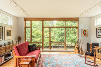 Example of a trendy medium tone wood floor and brown floor living room design in DC Metro with white walls