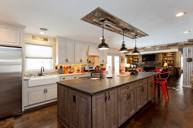 This is an example of a large country l-shaped open plan kitchen in DC Metro with a farmhouse sink, raised-panel cabinets, white cabinets, granite benchtops, multi-coloured splashback, matchstick tile splashback, stainless steel appliances, dark hardwood floors, with island, brown floor and multi-coloured benchtop.