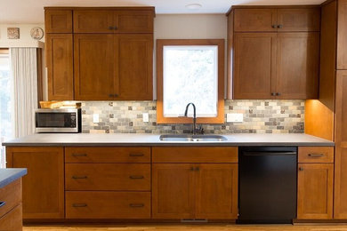 Inspiration for a mid-sized craftsman u-shaped light wood floor kitchen remodel in Other with an integrated sink, flat-panel cabinets, medium tone wood cabinets, gray backsplash, ceramic backsplash, black appliances, a peninsula and concrete countertops