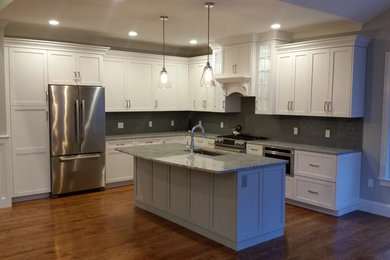 Example of a mid-sized classic l-shaped medium tone wood floor eat-in kitchen design in Boston with an undermount sink, shaker cabinets, white cabinets, granite countertops, gray backsplash, glass tile backsplash, stainless steel appliances and an island