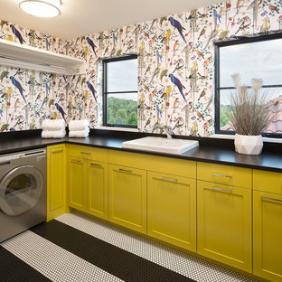 Ejemplo de cuarto de lavado en L, mediterráneo, con fregadero encastrado, armarios estilo shaker, puertas de armario amarillas, paredes multicolor, suelo multicolor y encimeras negras