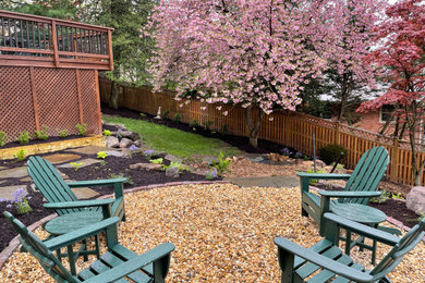 Photo of a mid-sized rustic partial sun backyard gravel landscaping in DC Metro with a fire pit.
