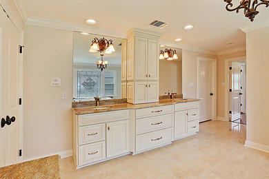 Drop-in bathtub - large traditional master beige floor and limestone floor drop-in bathtub idea in New Orleans with raised-panel cabinets, white cabinets, beige walls, an undermount sink and granite countertops