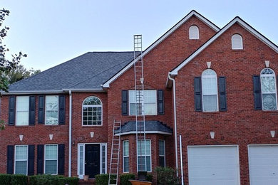 Example of a large classic red two-story brick house exterior design in Atlanta with a hip roof and a shingle roof