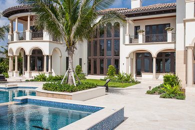 Photo of a large mediterranean backyard custom-shaped pool in Miami with a hot tub and tile.