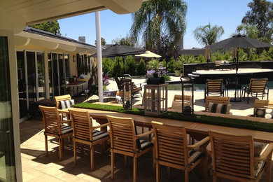 This is an example of a large arts and crafts backyard patio in San Diego with a water feature, natural stone pavers and an awning.