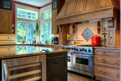 Elegant kitchen photo in Seattle with raised-panel cabinets, medium tone wood cabinets, beige backsplash and stainless steel appliances