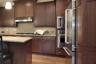 Mid-sized trendy l-shaped medium tone wood floor eat-in kitchen photo in Toronto with an undermount sink, shaker cabinets, dark wood cabinets, granite countertops, beige backsplash, stone tile backsplash, stainless steel appliances and an island