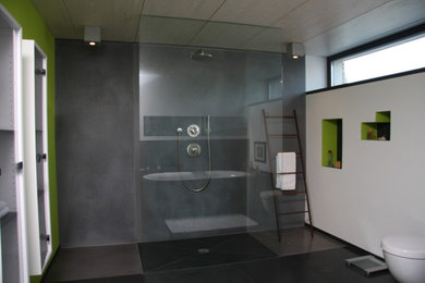 This is an example of a contemporary master bathroom in Other with a drop-in tub, a curbless shower, a two-piece toilet, white walls and slate floors.