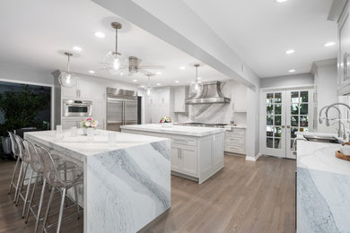 Example of a large transitional brown floor and exposed beam eat-in kitchen design in Chicago with an undermount sink, beaded inset cabinets, white cabinets, quartz countertops, white backsplash, quartz backsplash, stainless steel appliances, two islands and white countertops