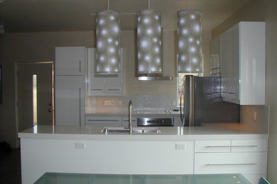 Inspiration for a mid-sized modern u-shaped medium tone wood floor eat-in kitchen remodel in Albuquerque with an undermount sink, flat-panel cabinets, white cabinets, quartzite countertops, white backsplash, stone tile backsplash, stainless steel appliances and a peninsula