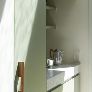 メルボルンのコンテンポラリースタイルのおしゃれな家事室 (シングルシンク、緑のキャビネット、テラゾーカウンター、白い壁、セラミックタイルの床、上下配置の洗濯機・乾燥機、グレーの床、グレーのキッチンカウンター) の写真