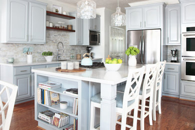 Eat-in kitchen - large traditional u-shaped medium tone wood floor and orange floor eat-in kitchen idea in Houston with a drop-in sink, raised-panel cabinets, blue cabinets, quartz countertops, multicolored backsplash, marble backsplash, stainless steel appliances, an island and white countertops