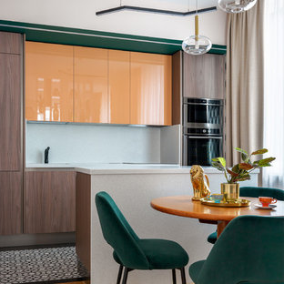 Aménagement d'une cuisine américaine linéaire contemporaine avec un placard à porte plane, des portes de placard oranges, une crédence blanche, un îlot central, un sol multicolore, un plan de travail blanc et un électroménager en acier inoxydable.