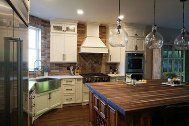 Example of a large transitional l-shaped medium tone wood floor and brown floor eat-in kitchen design in Orange County with a farmhouse sink, shaker cabinets, beige cabinets, wood countertops, brick backsplash, stainless steel appliances, an island and white countertops