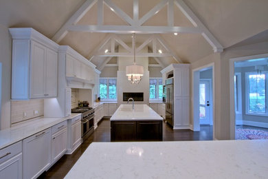 Example of a huge classic dark wood floor and brown floor eat-in kitchen design in Indianapolis with an undermount sink, recessed-panel cabinets, white cabinets, quartz countertops, beige backsplash, ceramic backsplash, stainless steel appliances and two islands
