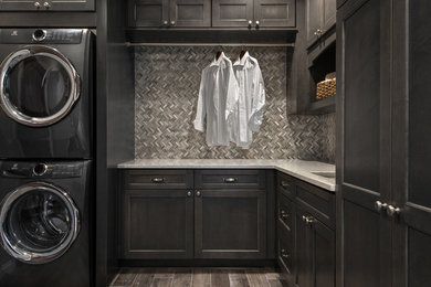 Mid-sized transitional l-shaped porcelain tile laundry room photo in Detroit with an undermount sink, flat-panel cabinets, dark wood cabinets, quartz countertops, beige walls and a stacked washer/dryer