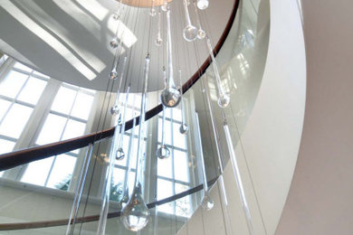This is an example of a modern spiral wood railing staircase in Other with limestone treads, limestone risers, wallpapered walls and feature lighting.