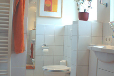 Photo of a small contemporary bathroom in Other with white cabinets, an alcove shower, a two-piece toilet, white tiles, ceramic tiles, beige walls, ceramic flooring and a trough sink.
