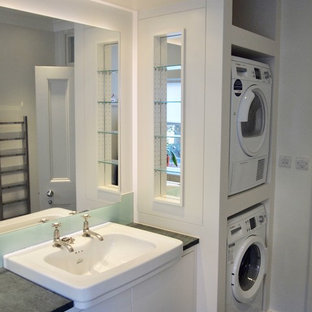 ロンドンの中サイズのコンテンポラリースタイルのおしゃれな家事室 (ドロップインシンク、フラットパネル扉のキャビネット、白いキャビネット、御影石カウンター、白い壁、スレートの床、上下配置の洗濯機・乾燥機、緑の床、グレーのキッチンカウンター) の写真