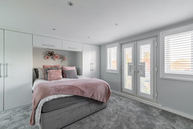 Contemporary grey and pink loft bedroom in Essex with grey walls, carpet, grey floors and a vaulted ceiling.