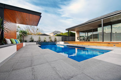 This is an example of a large contemporary front yard custom-shaped natural pool in Adelaide with natural stone pavers.