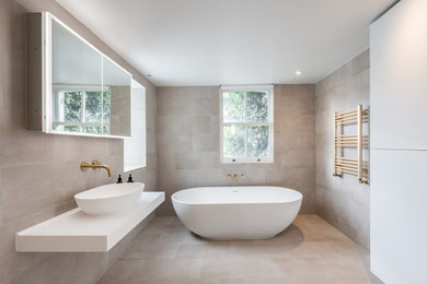Photo of a family bathroom in London with a freestanding bath, a corner shower, a wall mounted toilet, beige tiles, porcelain tiles, beige walls, porcelain flooring, a wall-mounted sink, beige floors, a hinged door, white worktops and a single sink.