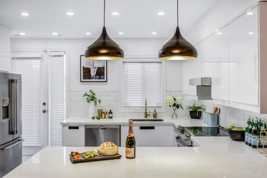 This is an example of a mid-sized contemporary u-shaped eat-in kitchen in Toronto with an undermount sink, flat-panel cabinets, white cabinets, quartz benchtops, white splashback, stainless steel appliances, porcelain floors and white benchtop.