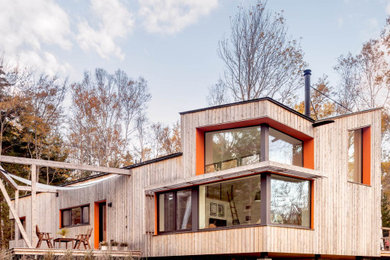 Imagen de fachada de casa beige actual de dos plantas con revestimiento de madera y techo de mariposa