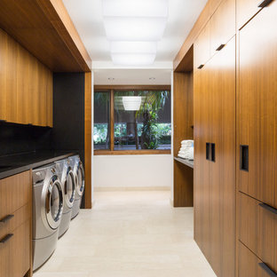 ニューヨークの大きいモダンスタイルのおしゃれな家事室 (ダブルシンク、フラットパネル扉のキャビネット、中間色木目調キャビネット、御影石カウンター、左右配置の洗濯機・乾燥機) の写真