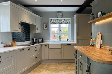 This is an example of a small country enclosed kitchen in Oxfordshire with a belfast sink, shaker cabinets, quartz worktops, black splashback, ceramic splashback, porcelain flooring, no island, beige floors, white worktops, exposed beams and feature lighting.