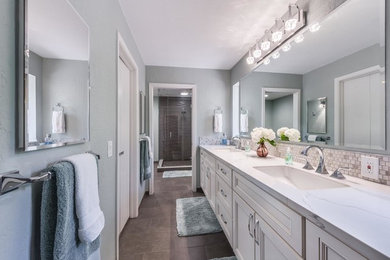 Mid-sized transitional master brown floor corner shower photo in Sacramento with recessed-panel cabinets, white cabinets, gray walls, an undermount sink, quartzite countertops, a hinged shower door and white countertops