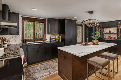 Example of a mid-sized transitional light wood floor kitchen design in Detroit with a drop-in sink, black cabinets, quartz countertops, paneled appliances and an island