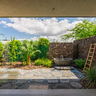 Photo of a mid-sized tropical backyard patio in Hawaii with natural stone pavers, no cover and an outdoor shower.