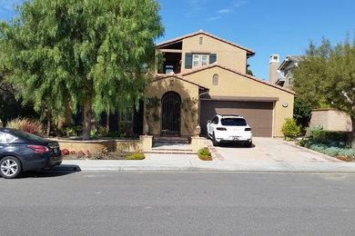 Large mediterranean brown two-story stucco exterior home idea in Orange County with a shingle roof