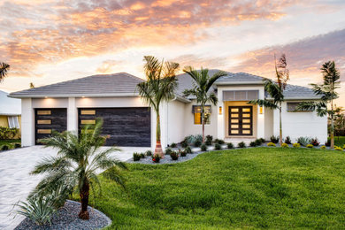 Inspiration for a modern white one-story house exterior remodel in Miami with a hip roof, a tile roof and a gray roof
