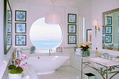 Trendy gray tile freestanding bathtub photo with shaker cabinets, white cabinets, white walls, an undermount sink and marble countertops